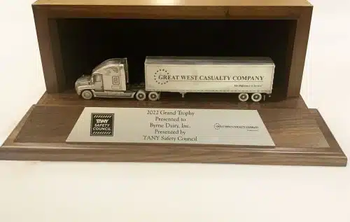 a wooden plaque with a silver model of a tractor trailer - the trophy representing the Grand Champion of the Trucking Association of New York Safety Council (TSC) Fleet Safety Awards